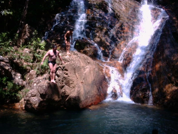 some women in bikinis near a waterfall