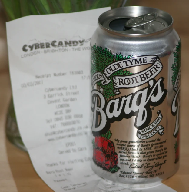 a can of beer sits on a table beside receipt
