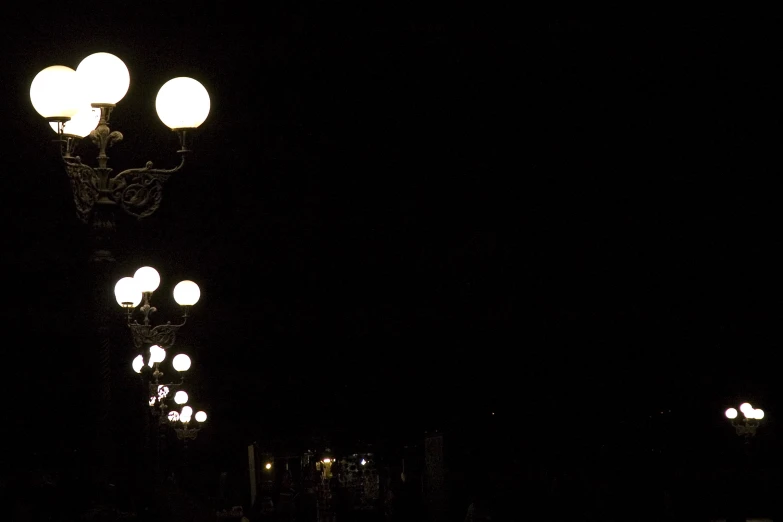 street lights are lit up on a dark street
