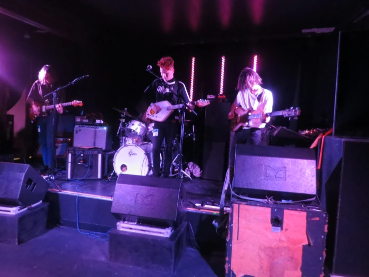 a group of young people standing on stage with guitars