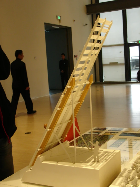 a model of a ladder with people walking past it