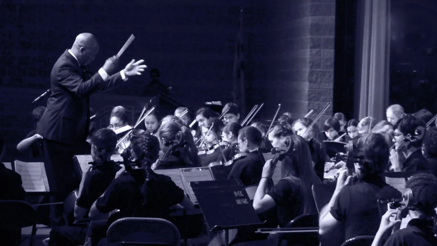 a conductor with his orchestra in front of a crowd