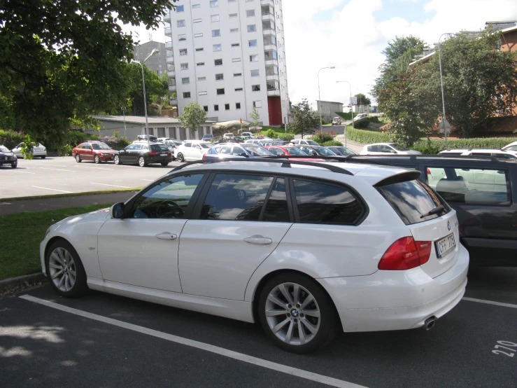 a white bmw parked in a parking space with cars in the background