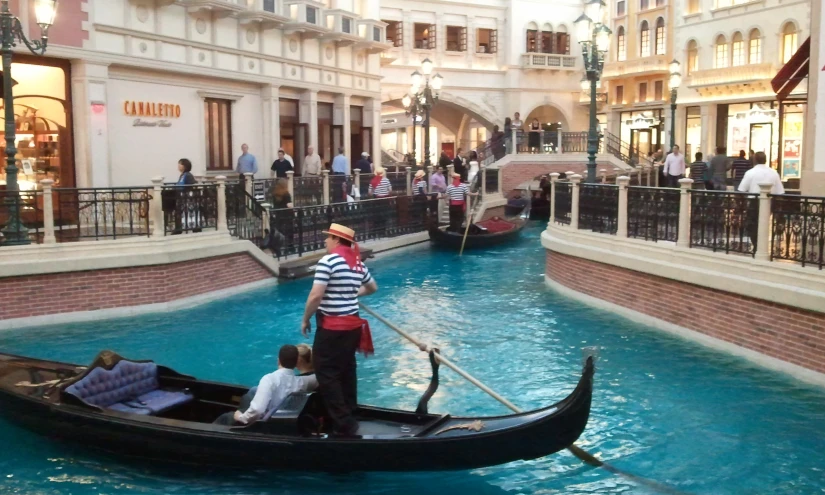 a man standing on the back of a gondola as it rides through a city