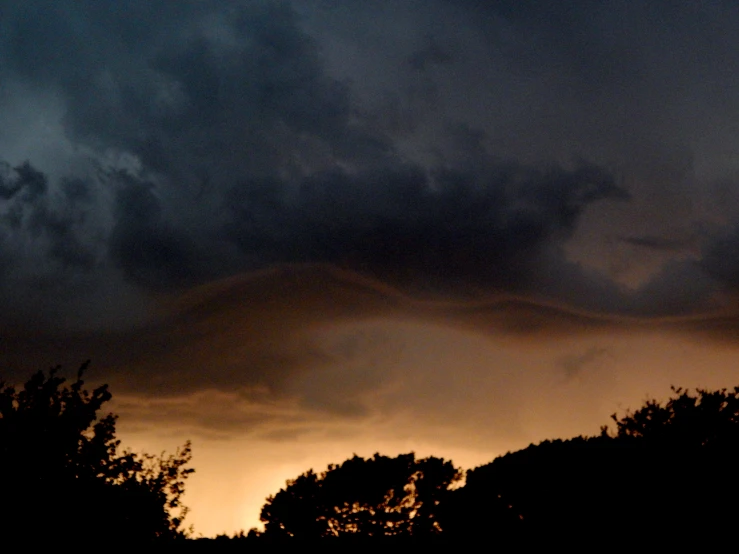 a dark storm is coming down over a hill