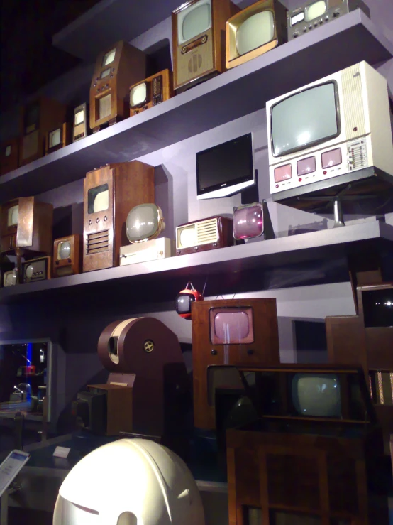 a room that has many different types of old tvs on shelves