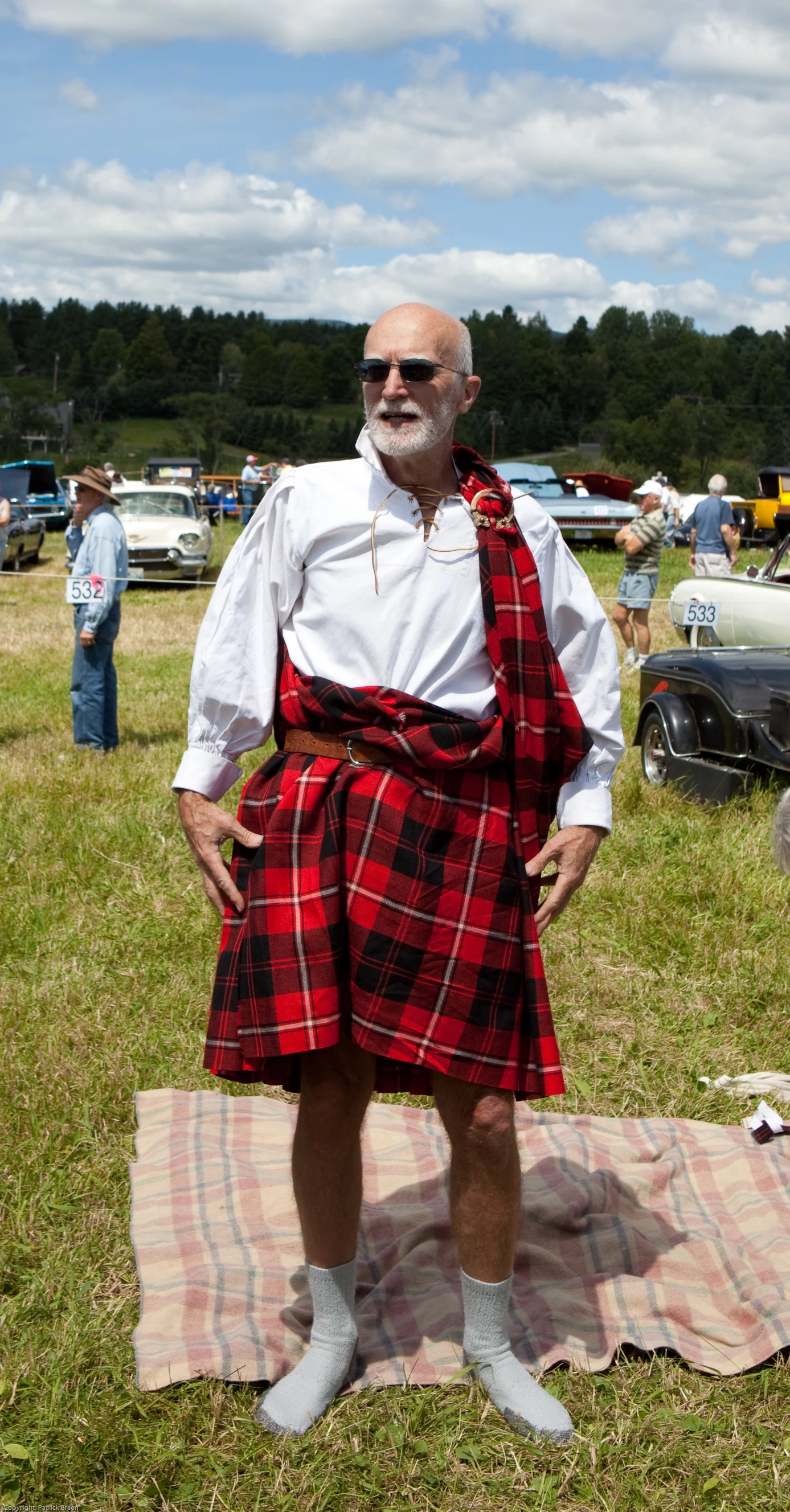 a man in a kilt standing in the grass