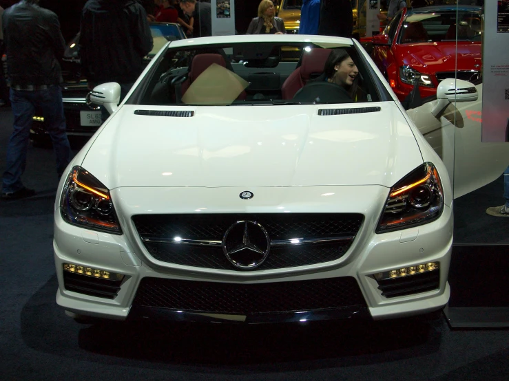 people are looking at a mercedes car on display