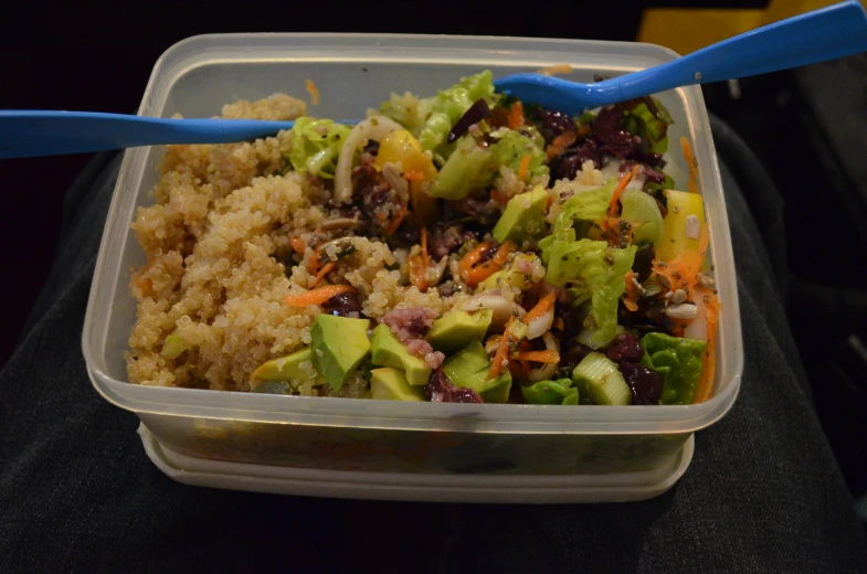 a tray with broccoli and rice and a blue spoon