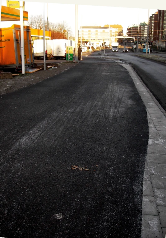 a paved city street next to a train crossing