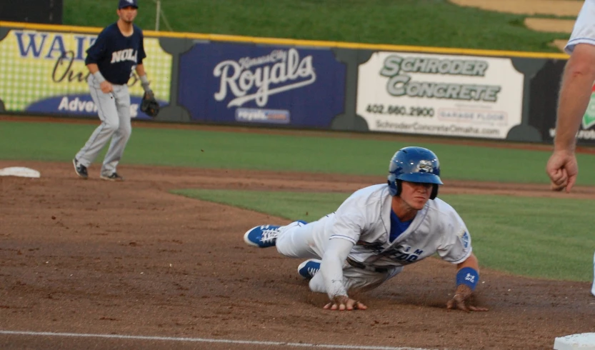 baseball player dives back to catch the ball while a catcher stands nearby