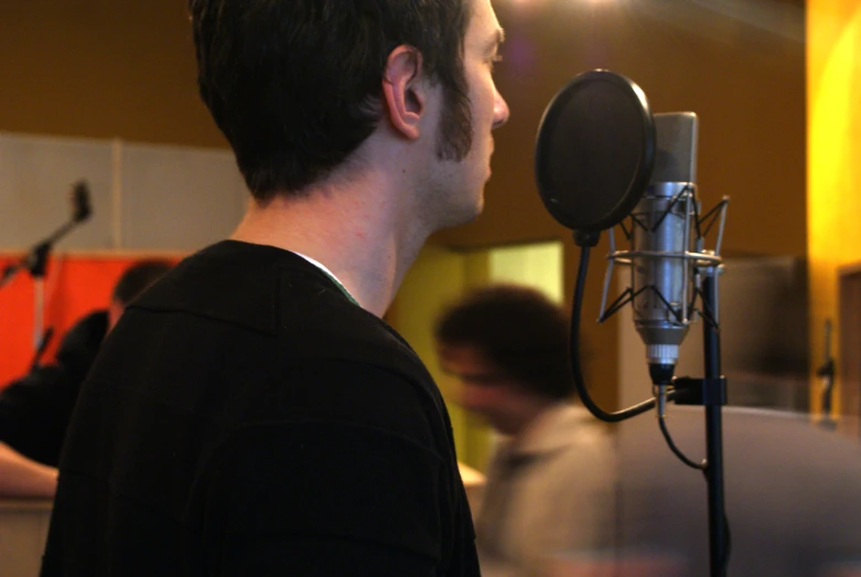 a person with earbuds stands in front of a recording microphone