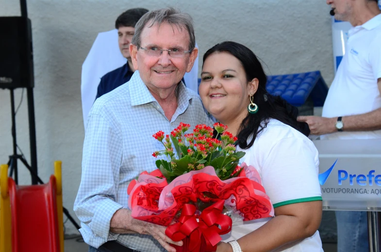 a man and woman are standing together holding some flowers