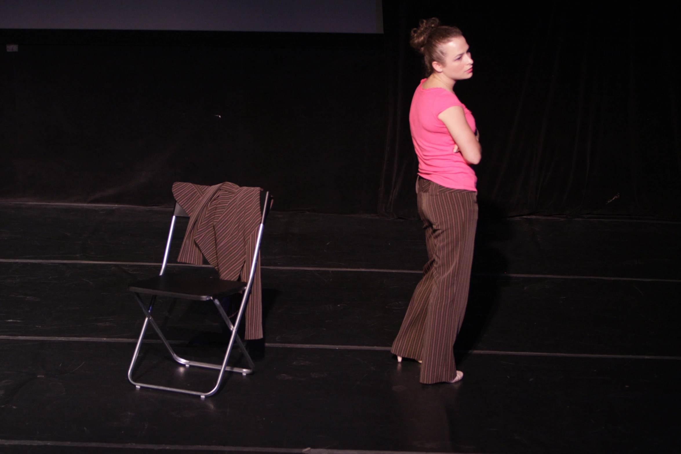 a woman stands in front of a chair on a stage