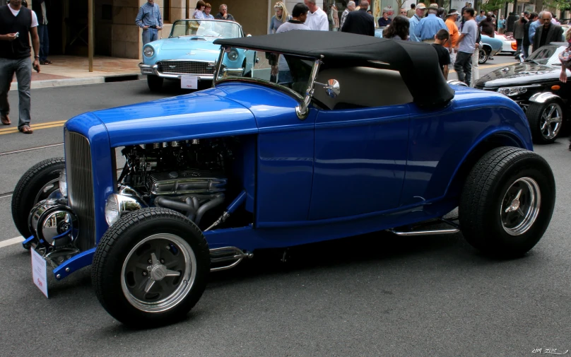 an antique style blue car parked on the side of a road