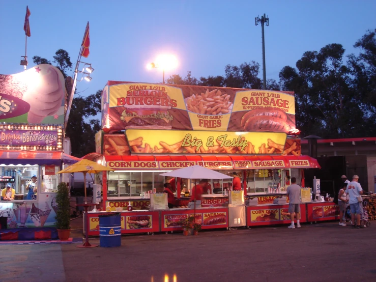 a couple of food stands with people and an umbrella