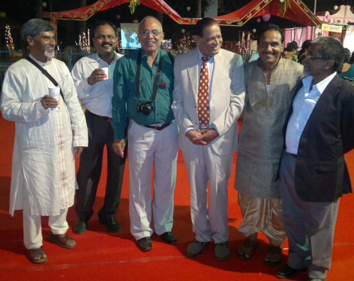 an indian group of men standing together in front of a red carpet