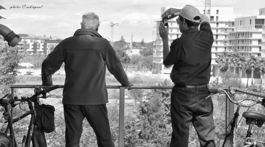 two older men looking at the trees with their bicycles