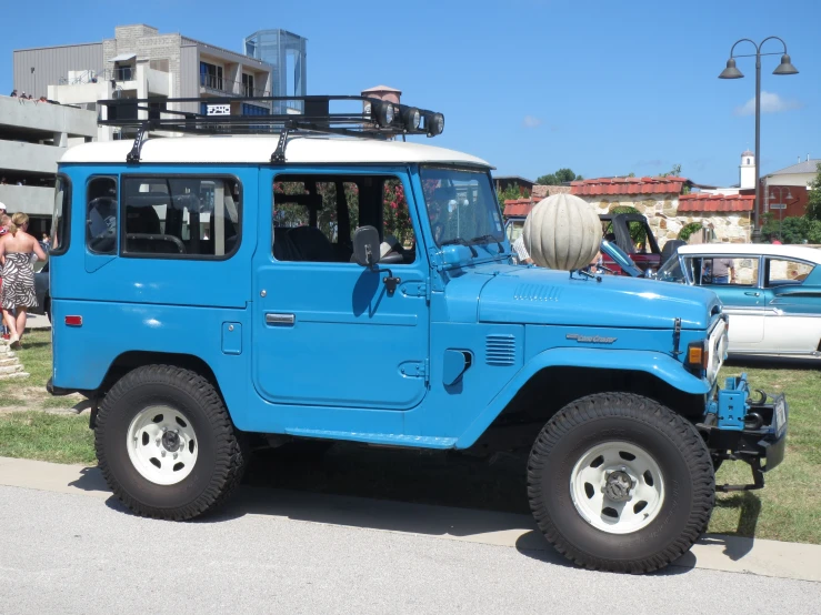 the light blue jeep is parked by the building