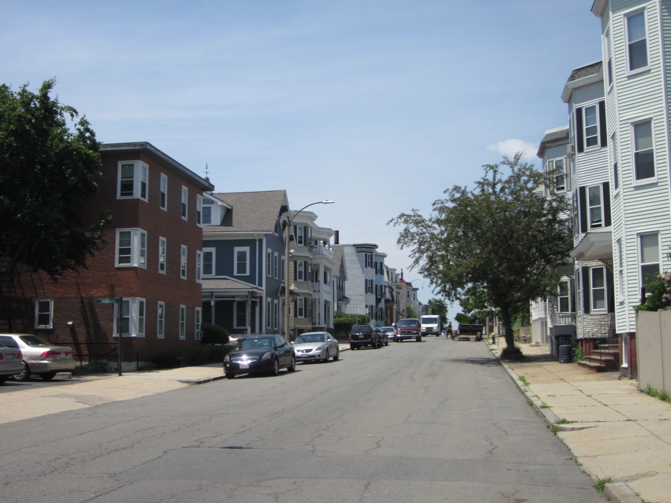 many cars are parked on a street in front of some buildings