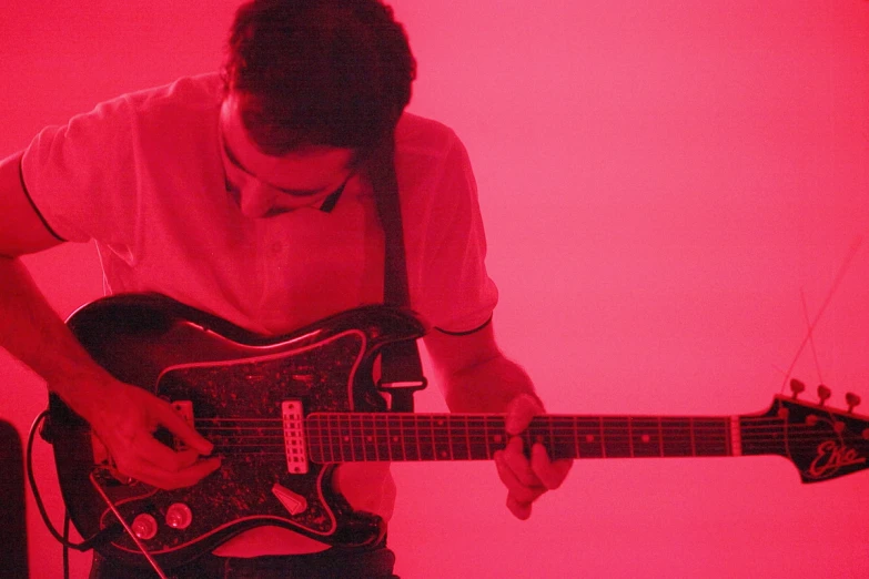 a man playing guitar in front of a red light