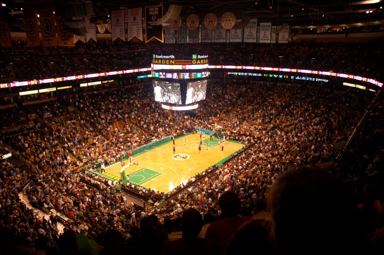 a crowd of people watch a basketball game in a darkened stadium