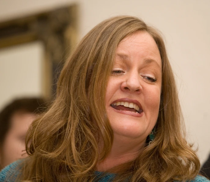 a woman smiling while holding her eyes closed