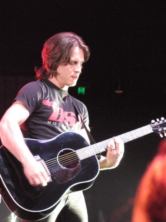 man playing an acoustic guitar in front of a crowd