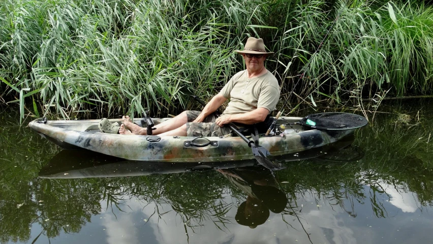 a man with hat is sitting in a canoe on the water