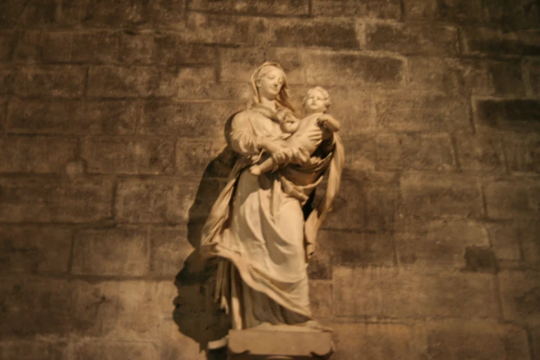 statue against a brick wall depicting the virgin mary and jesus