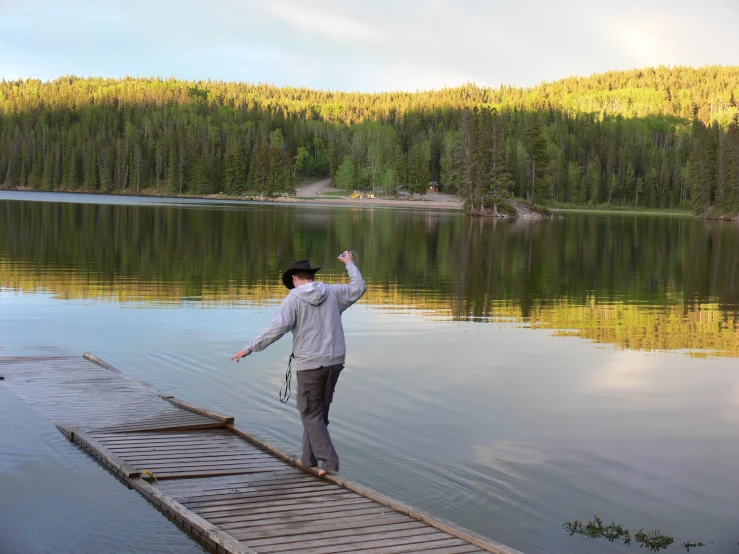 a man waving from the dock at a lake