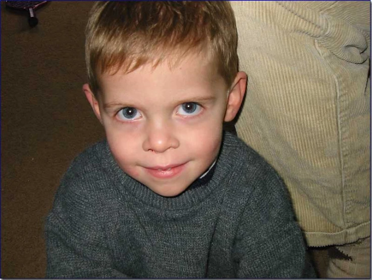 a close - up of a  wearing a grey sweater, with a smile on his face