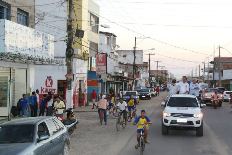 many people are riding bikes in front of cars and pedestrians