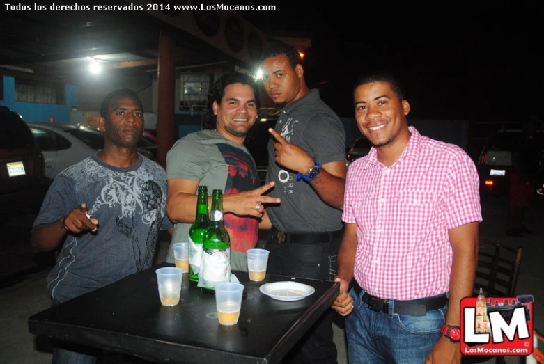 four men standing around a table with bottled wine