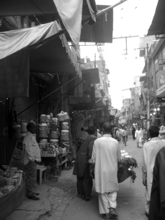 several people walk on a crowded street near vendors