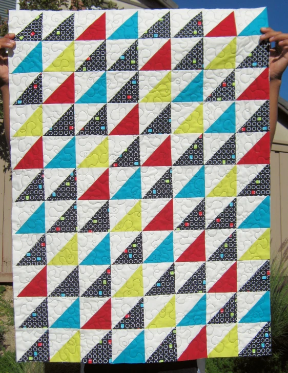 person holding up a piece of quilt with triangular shapes