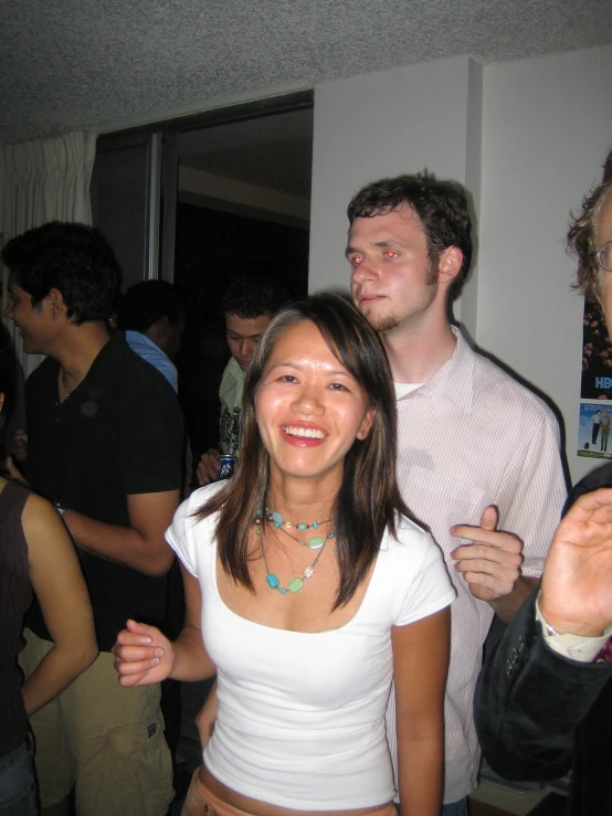 two young people are standing by a group of people in the hallway