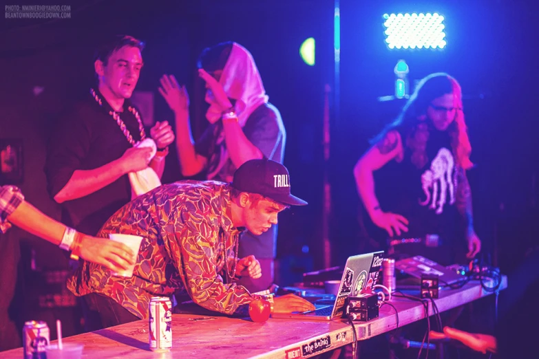 a dj performing on a wooden table with many people