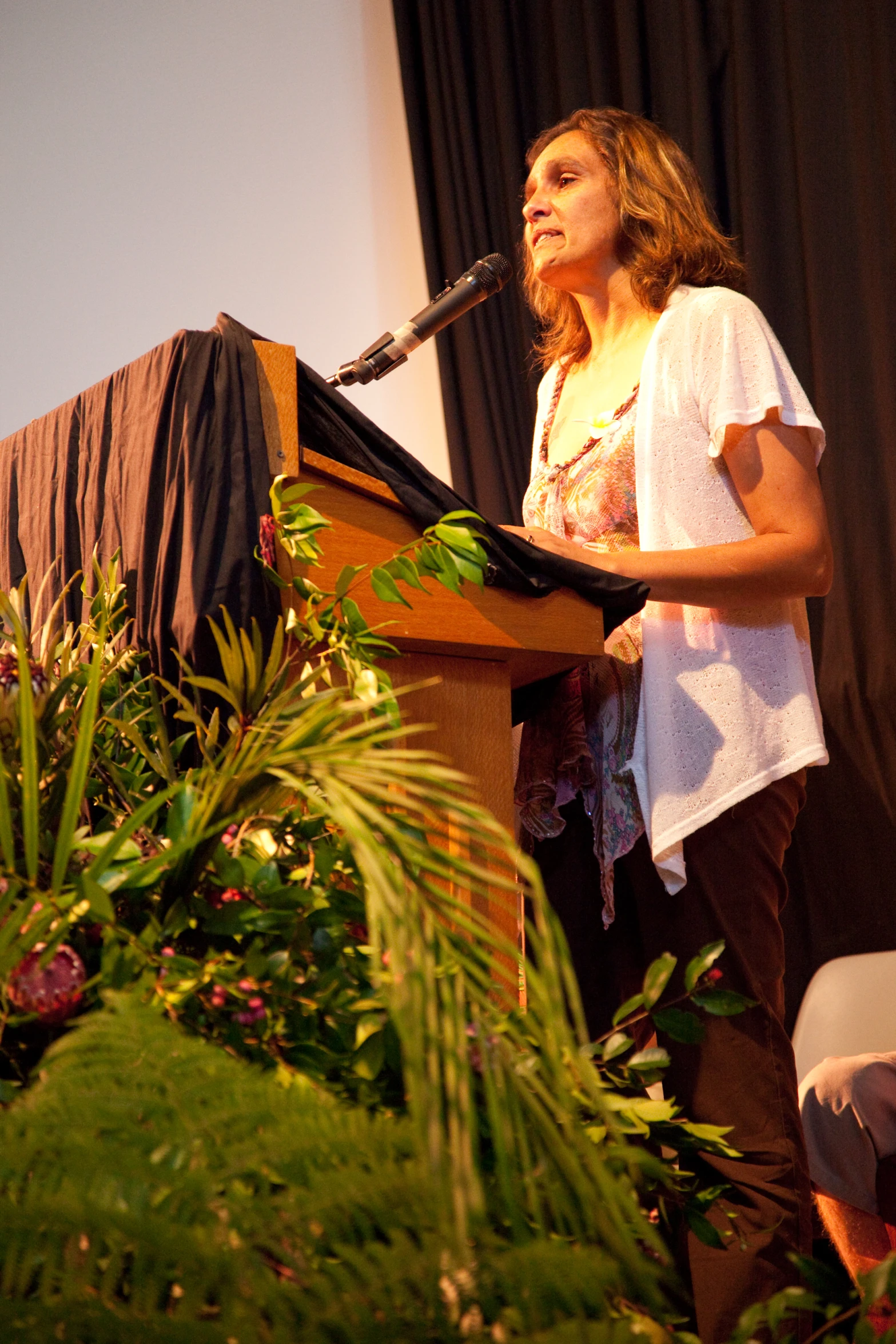 a woman standing at a podium speaking into a microphone