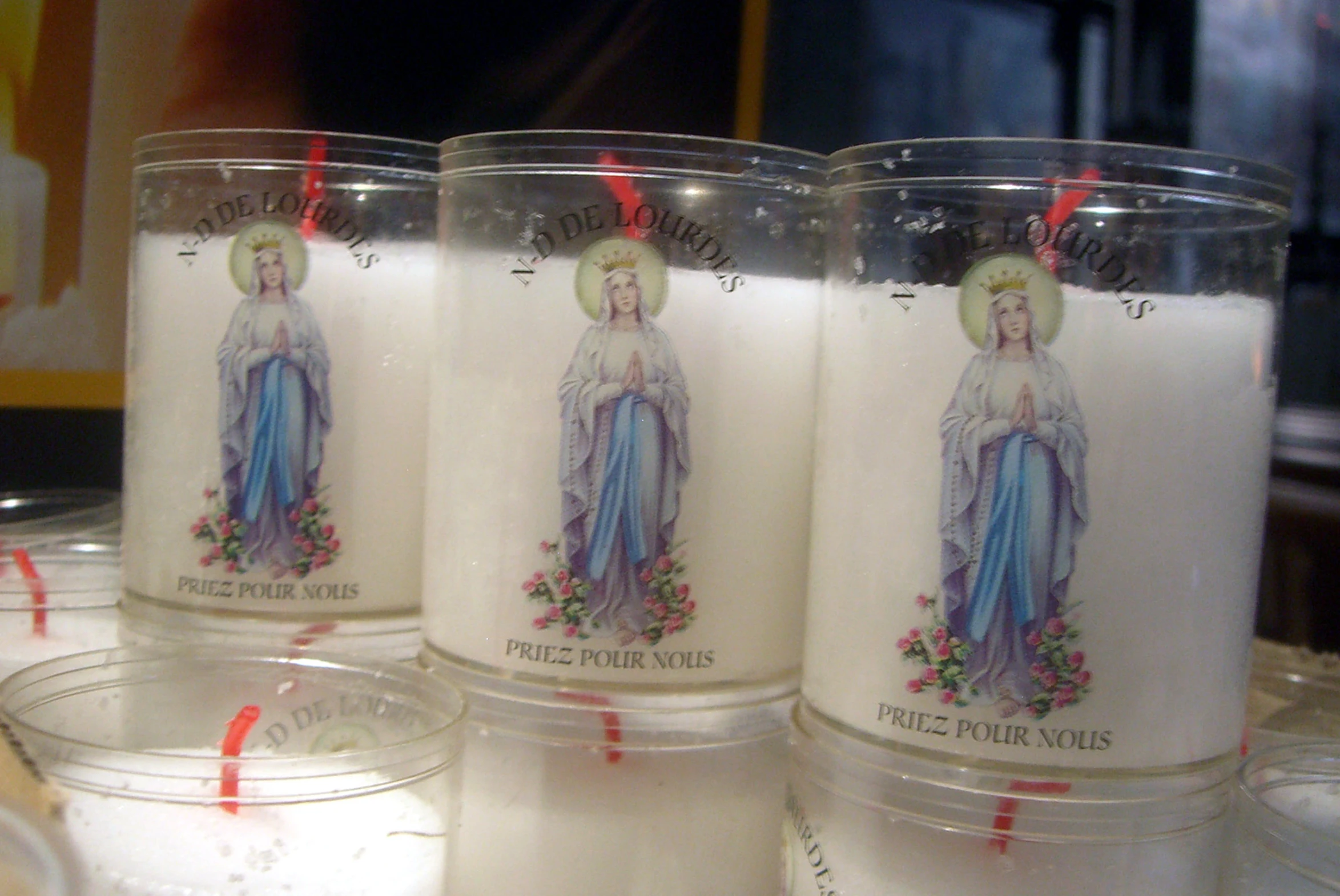 four candle jars with images of virgin mary