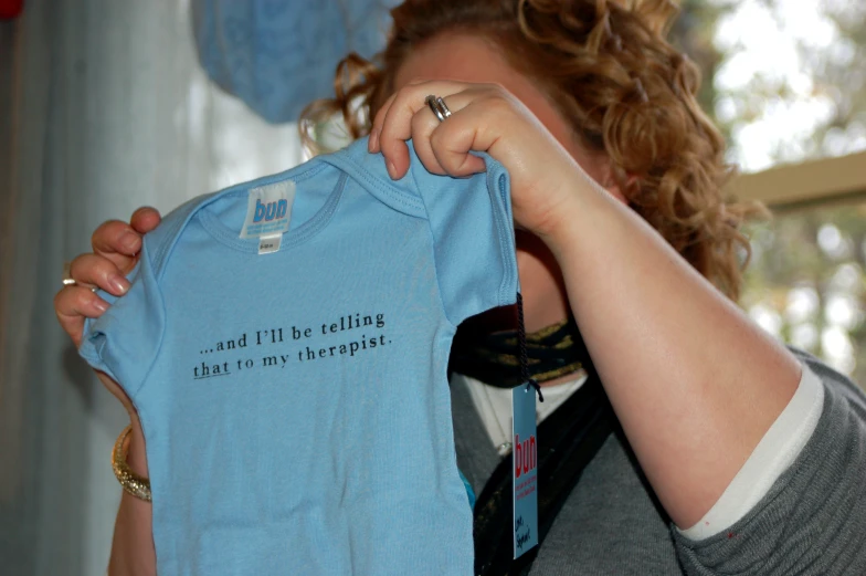 a woman holding up a blue shirt that says i'm not illegal