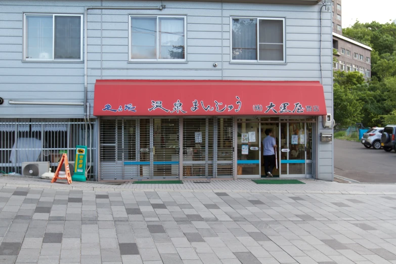 a man in a white shirt stands in front of a building with a red awning