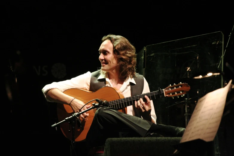 man with acoustic guitar sitting in front of microphone and playing