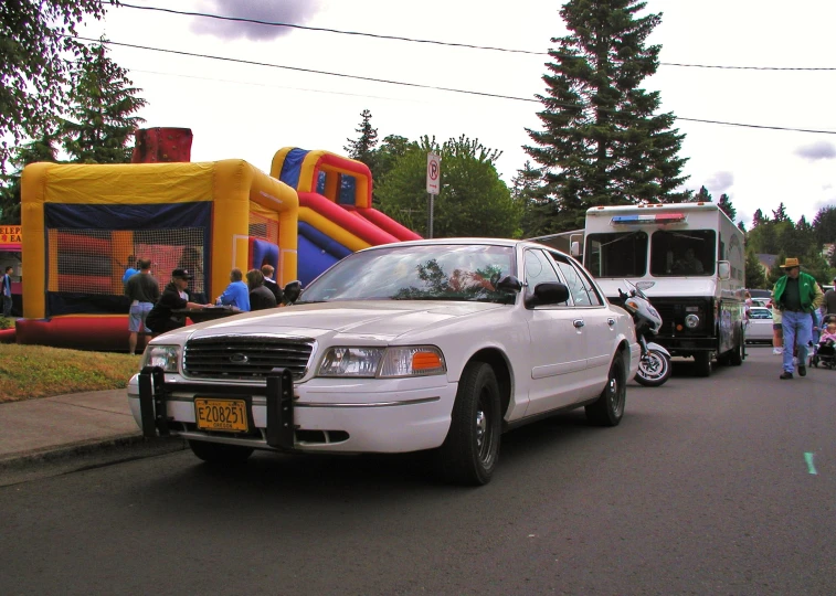 some cars and people are standing near inflatable bounches