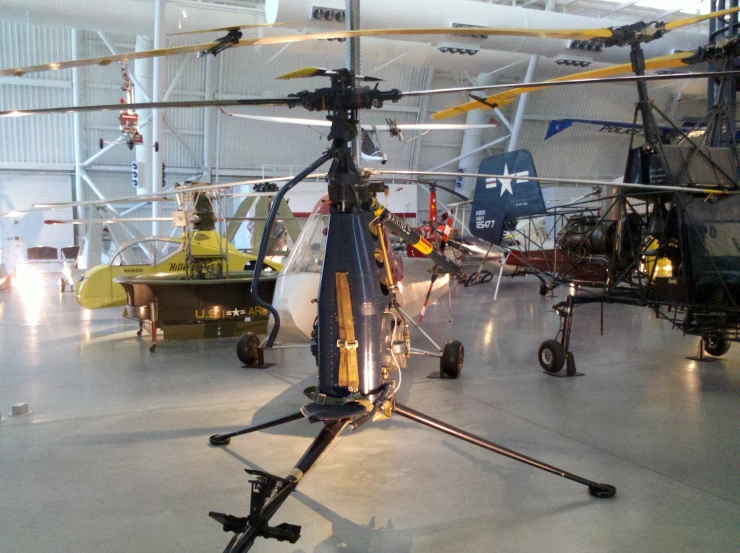 several small helicopter are parked in an empty hanger