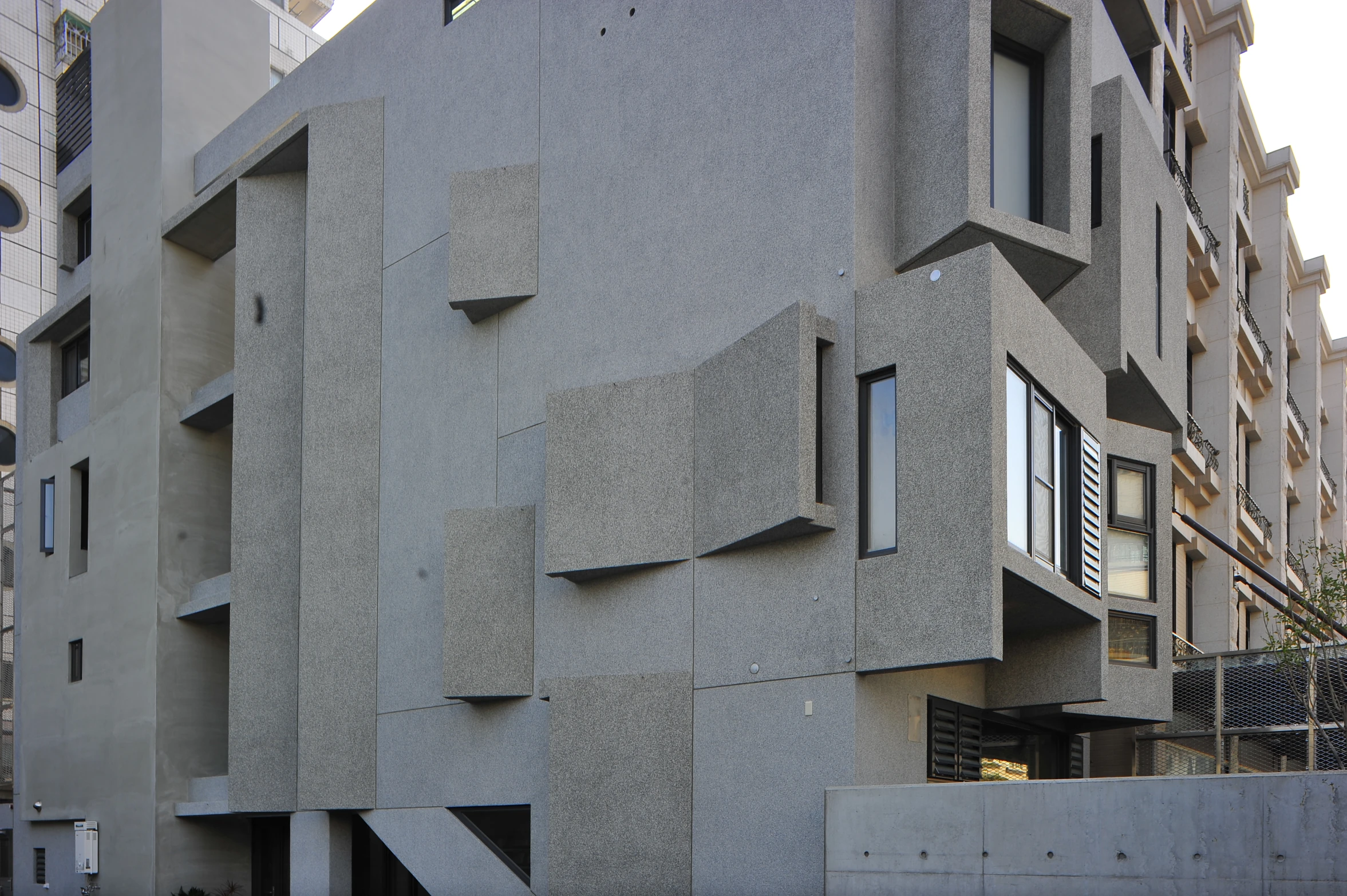 an apartment building has multiple square windows, and a gated courtyard