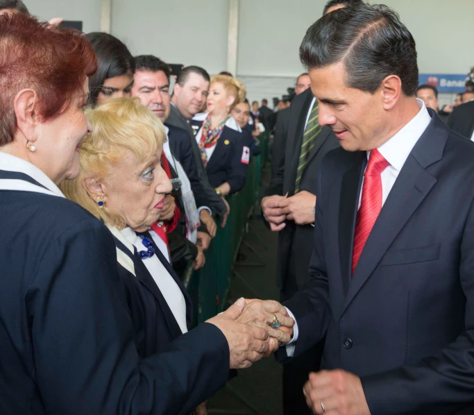 a man and woman are shaking hands in a room full of people