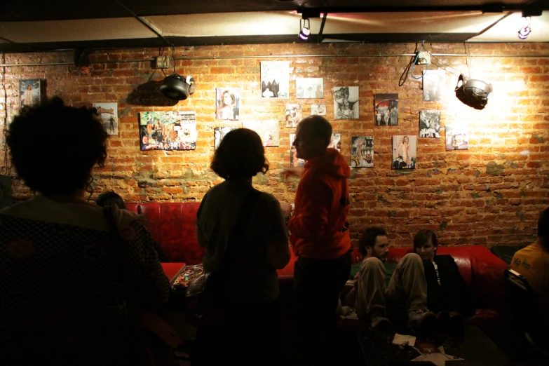 two people stand in front of a brick wall with images of women on it