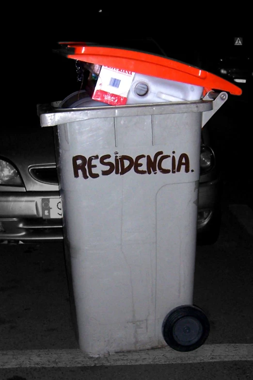 a garbage can sitting outside with a surfboard on top