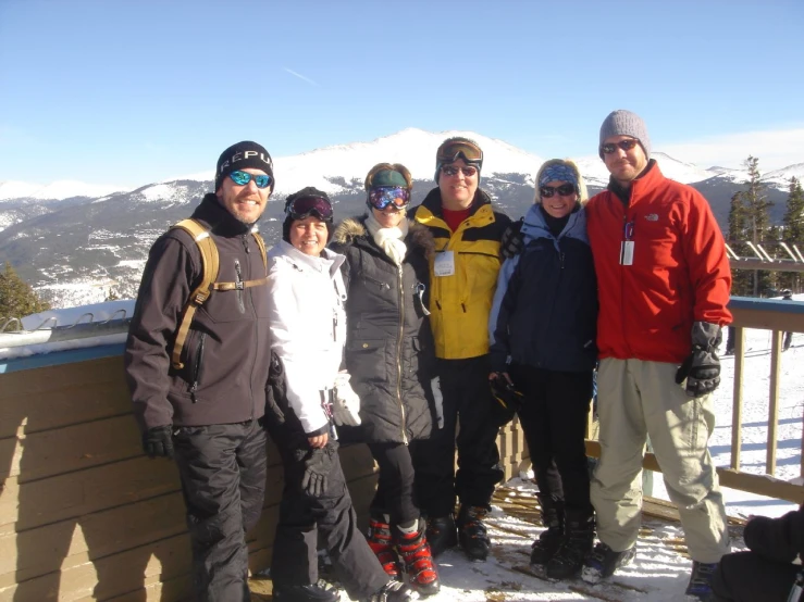 several people posing for a po on top of a ski slope